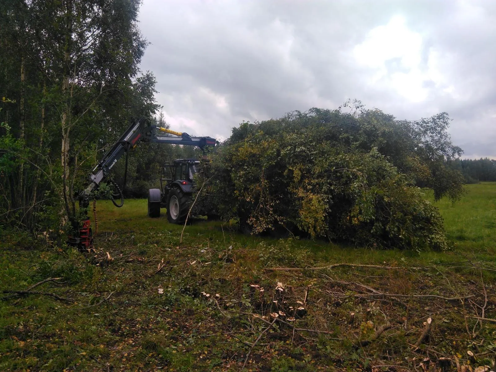 Tractor med kran röjer fält